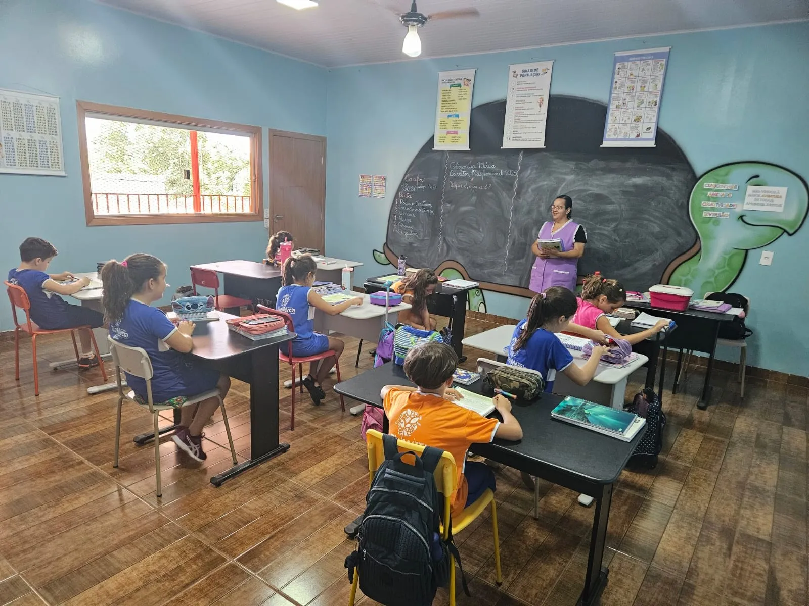 Professora dando aula para alunos de uniforme azul